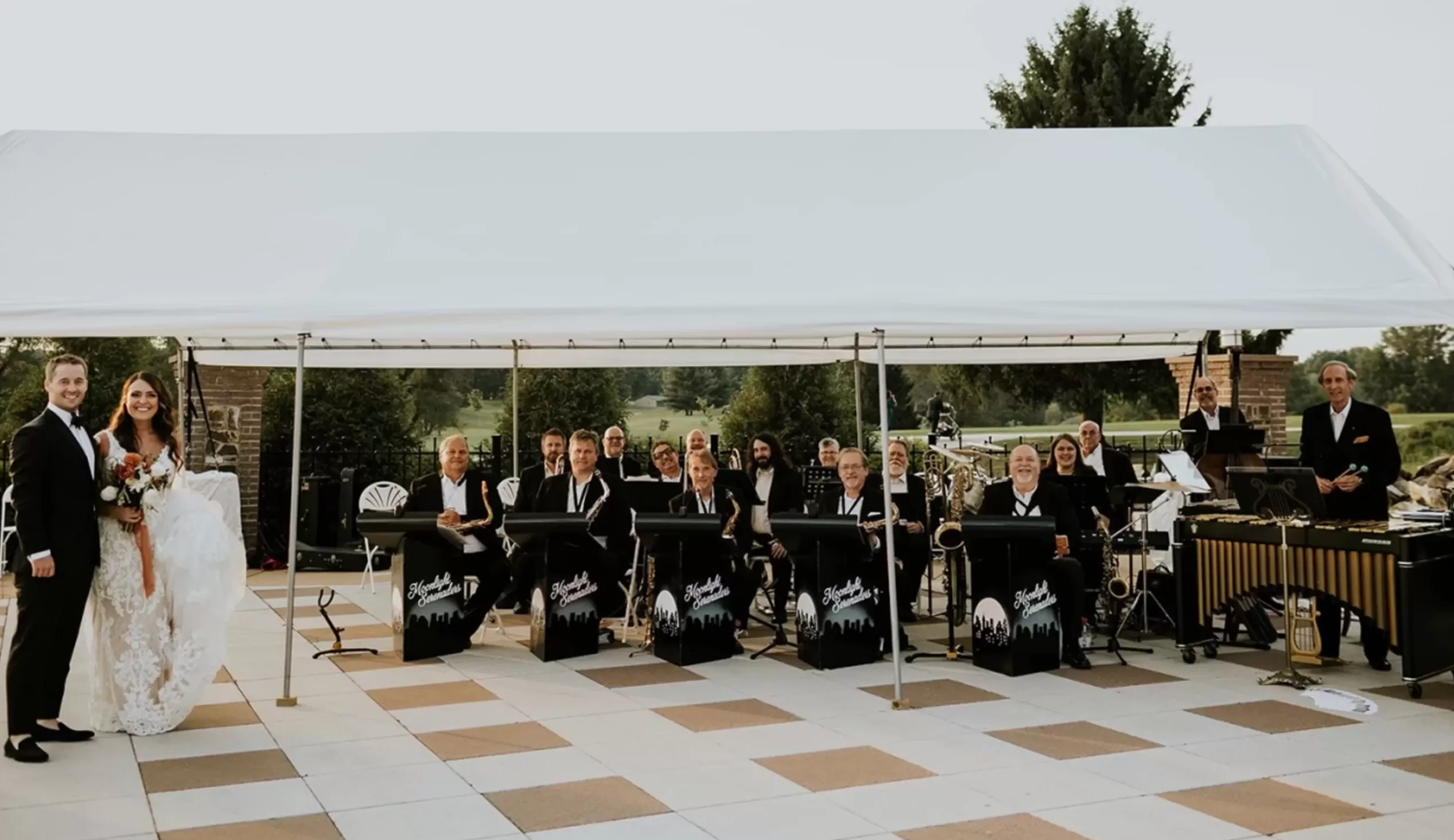 Group photo of The Moonlight Serenaders Big Band at a wedding client performance in an outdoor tent.